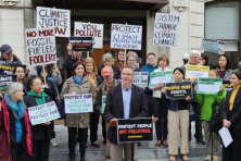 climate solutions board member tim miller speaking in front of cpp supporters holding signs 