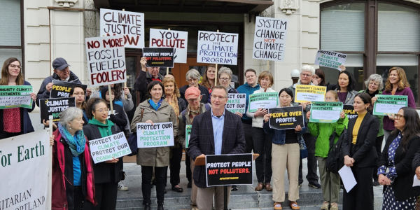 climate solutions board member tim miller speaking in front of cpp supporters holding signs 