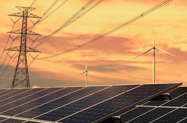 solar panels and wind turbines and transmission lines against a sunset backdrop