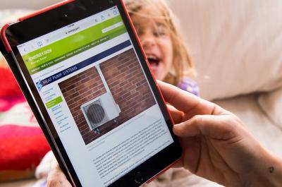 Photo of someone looking at heat pump systems on an iPad with a child in the background
