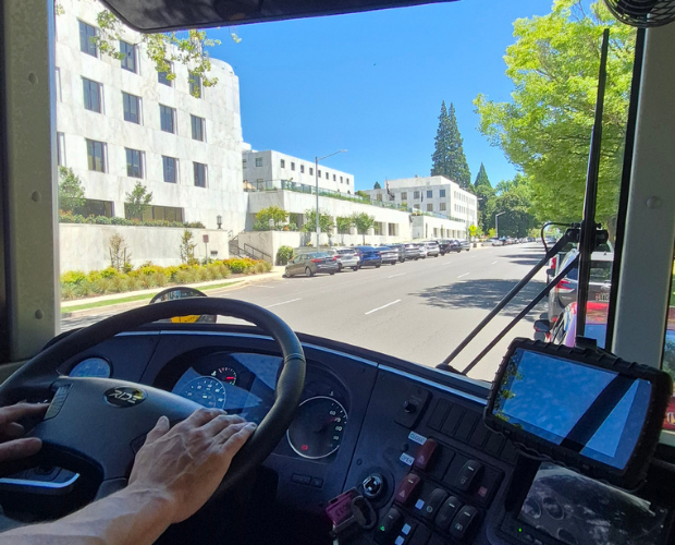A bus driver sitting in an electric school bus in front of the Oregon State Capitol.