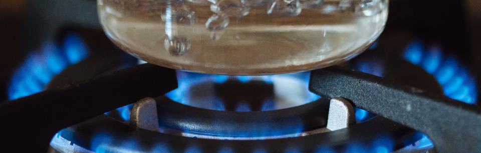 image of gas burner boiling clear glass pot of water