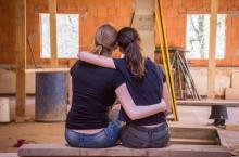 Photo of two women hugging in a house under construction