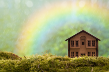 image of a small wooden house in a green field with a rainbow
