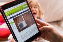 Photo of someone looking at heat pump systems on an iPad with a child in the background