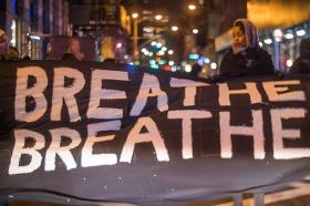woman holding protest sign saying &quot;breathe breathe&quot;